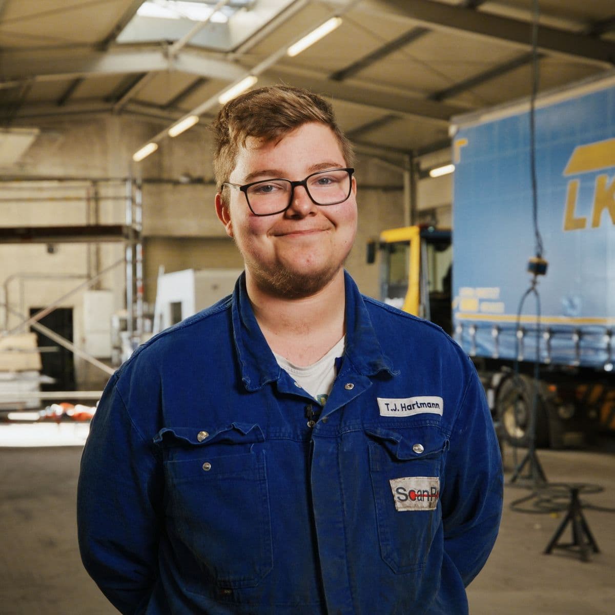 Kollege von ScanRo in blauer Arbeitsjacke in der Werkstatthalle
